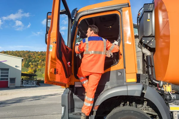 Garbage removal worker getting into the disposal vehicle — Stock Photo, Image