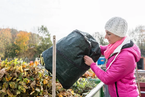 Žena, která dává odpad zelený do kontejneru v recyklačním středisku — Stock fotografie