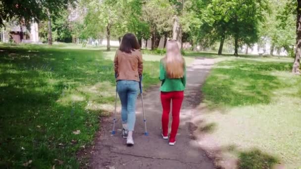 Υγιής γυναίκα και φίλος με σπασμένο πόδι περπάτημα μαζί — Αρχείο Βίντεο