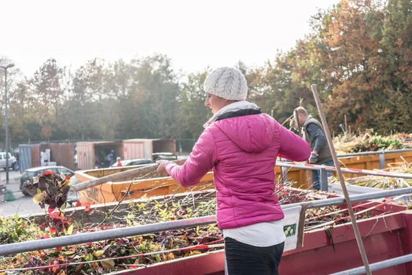 Femme donnant des déchets verts dans un conteneur au centre de recyclage — Photo