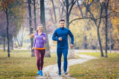 Kadın ve spor için sonbahar Park'ta koşan adam
