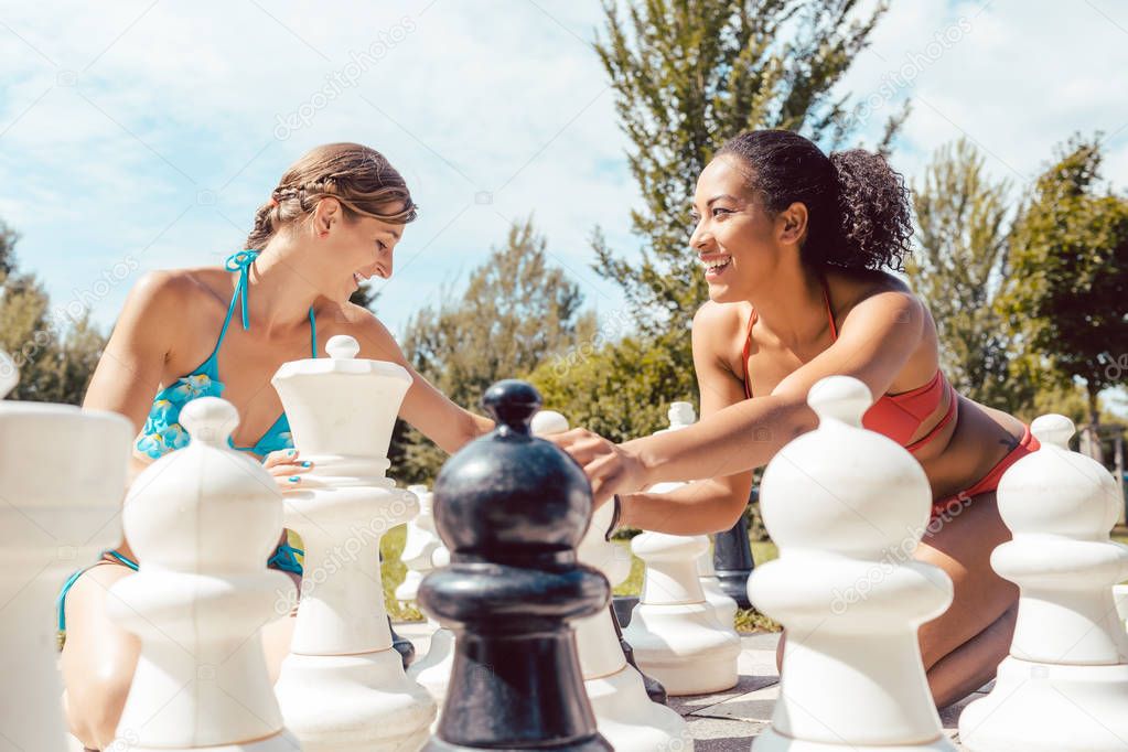 Smiling women playing big chess