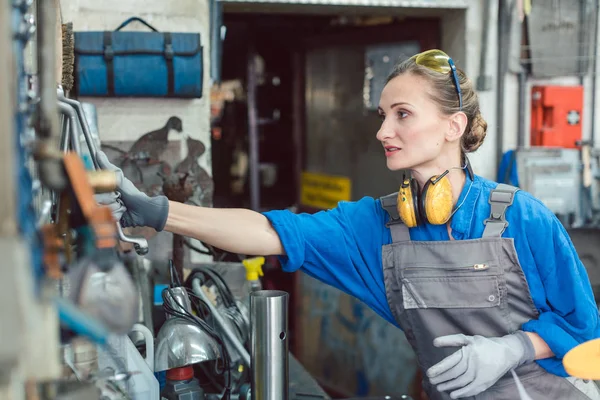 Metalworker woman in workshop grabbing tool — Stock Photo, Image