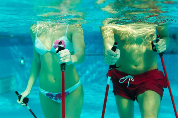 夫妇在游泳池与北欧步行棒锻炼 — 图库照片