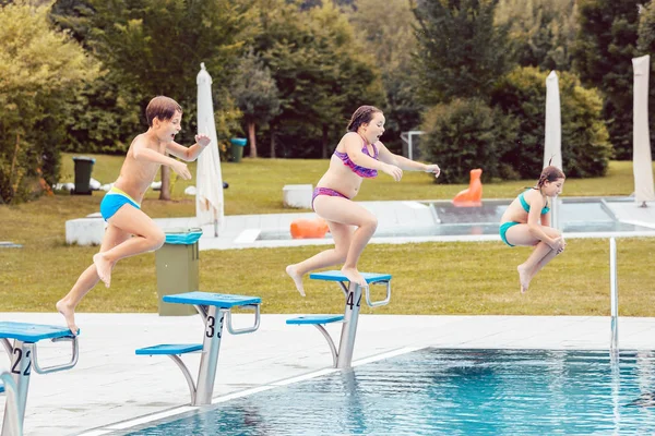 Grupo de niños saltando en la piscina — Foto de Stock
