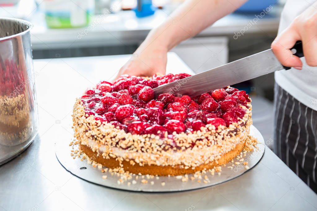 Close-up of woman confectioner cutting raspberry pie