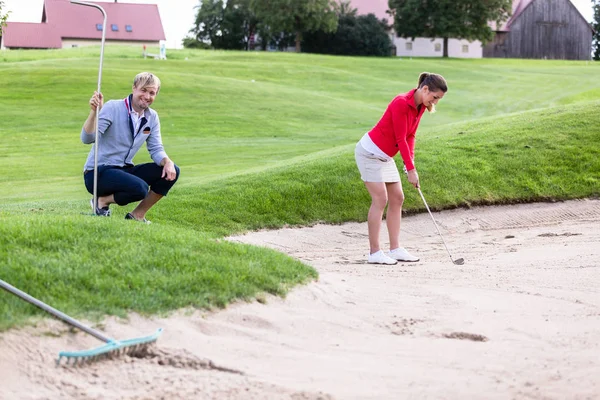 Freund sieht Golferin, die Golfball auf Bunker schlägt — Stockfoto