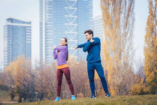 Sport couple doing warm-up exercise before starting a run