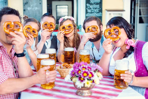 Grupo no jardim de cerveja da Baviera olhando através de buracos pretzel — Fotografia de Stock