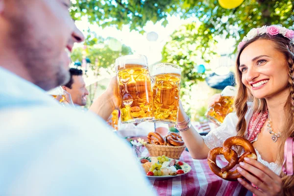 Casal copos clinking com enormes quantidades de cerveja no pub da Baviera — Fotografia de Stock