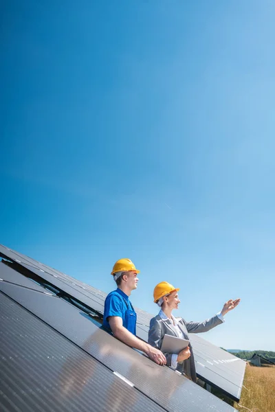 Trabalhador e gerente da fazenda solar olhando para o sol — Fotografia de Stock