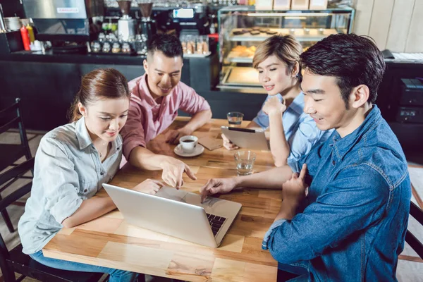 Amigos mirando el portátil en la cafetería — Foto de Stock