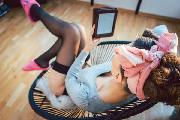 Wanita mengenakan kaus kaki dan sandal merah muda membaca buku di rumah — Stok Foto