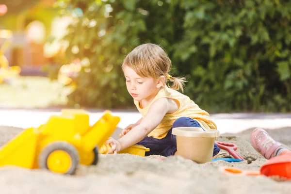 Little girl having lots of fun with her toys playing in the sandbox — Stock Photo, Image