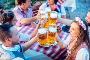 İnsanlar Bavyera bira bahçesinde yemek ve içkinin keyfini çıkarıyorlar.