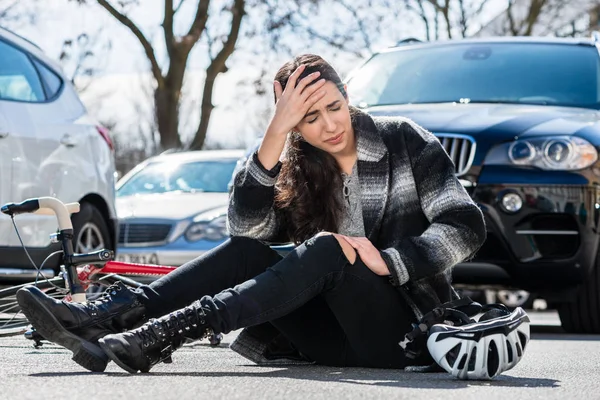 Młoda kobieta siedzi na asfalcie po wypadku rowerowym — Zdjęcie stockowe