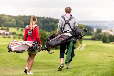 Golf çantası taşıyan çiftin arka görünümü