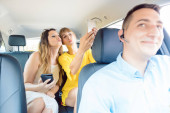 Frauen im Taxi machen Selfies mit ihren Handys