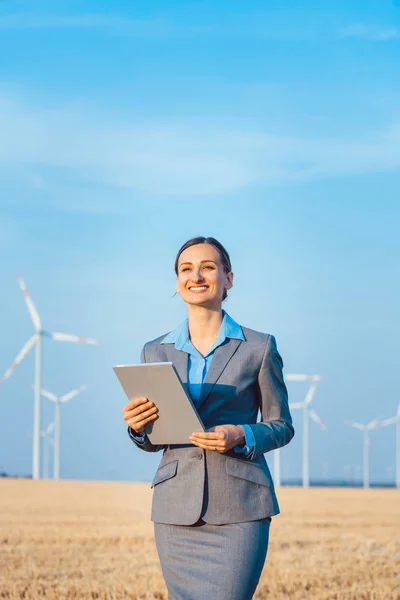 Investor in wind turbines with computer evaluating her investment on site — Stock Photo, Image