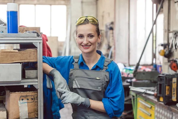 Mujer trabajadora en taller de metal mirando a la cámara — Foto de Stock