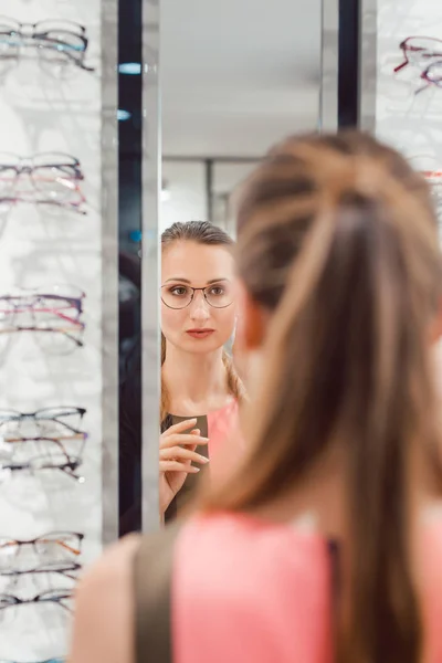 Jonge vrouw probeert modieuze bril in optometrist winkel — Stockfoto