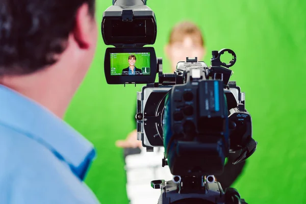 Kamery skierowane ku kobiety wiadomości lub reporter w zielonym pokoju studio — Zdjęcie stockowe