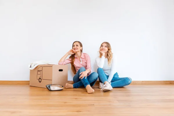 Duas mulheres no novo apartamento sonhando com como decorá-lo — Fotografia de Stock