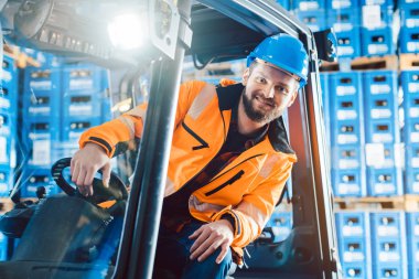 Lojistik dağıtım merkezinde forklift kullanan işçi