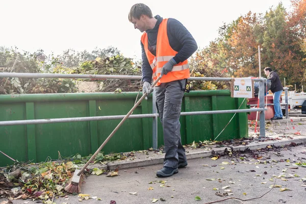 Mann fegt den Boden des Recyclingzentrums, nachdem er Grünabfälle abgeliefert hat — Stockfoto