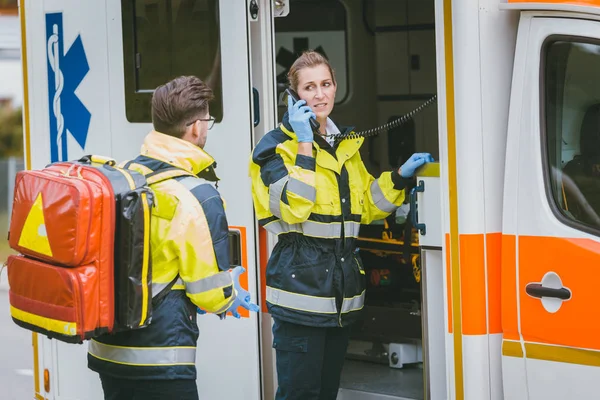 Médicos frente a ambulancia hablando con el cuartel general usando la radio — Foto de Stock