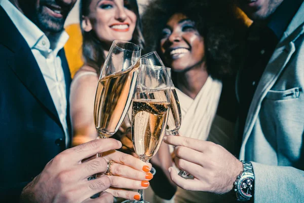 Men and women celebrating party while clinking glasses with sparkling wine — Stock Photo, Image