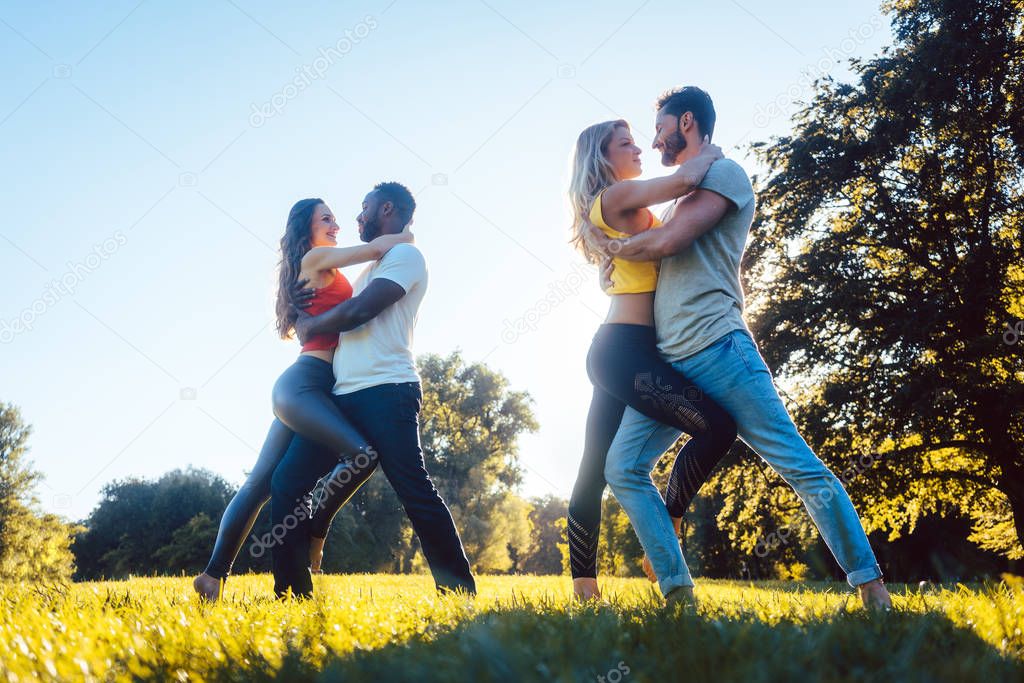 Women and men having fun dancing in the park