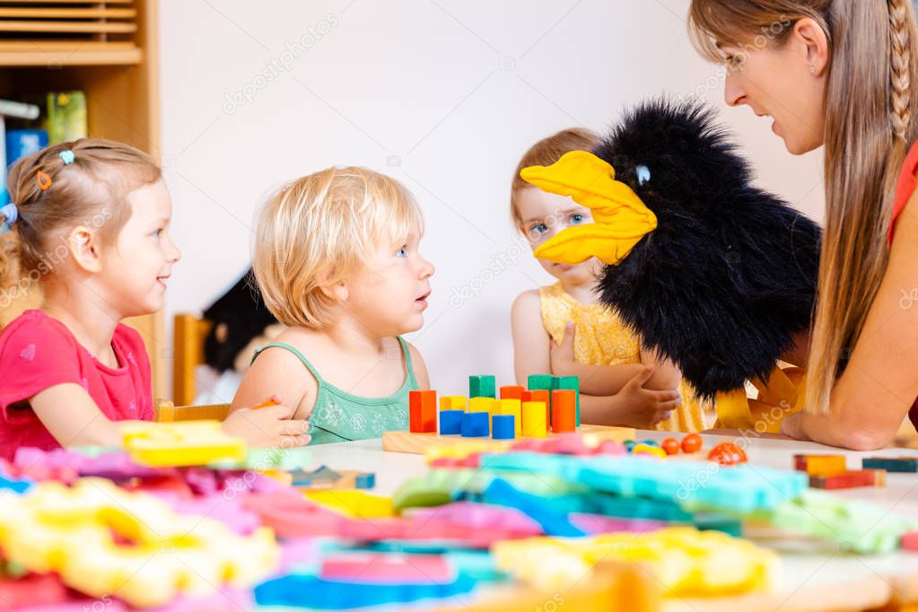 Kindergarten teacher and children playing with hand puppet