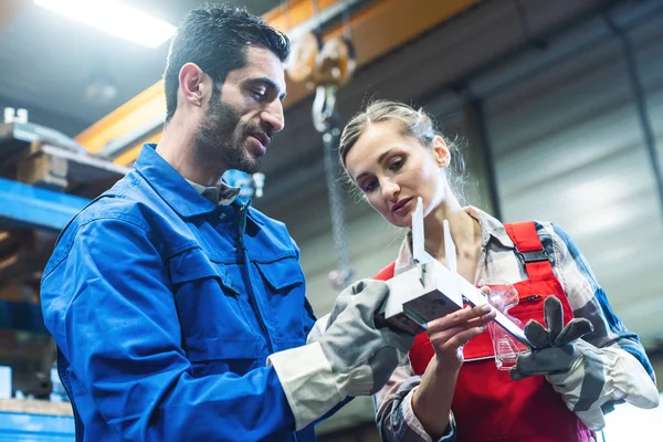 Arbeiterin und Mann prüfen Maße des Metallwerkstücks — Stockfoto