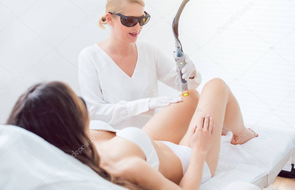 Woman in leg hair removal session at beauty parlor
