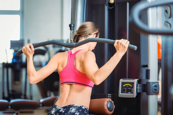 Fitte Frau, die in einem modernen Fitnessclub Lat-Liegestütze für die Rückenmuskulatur übt — Stockfoto