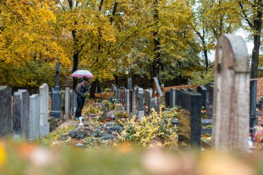 Graves on cemetery in autumn with a couple mourning the dead clipart