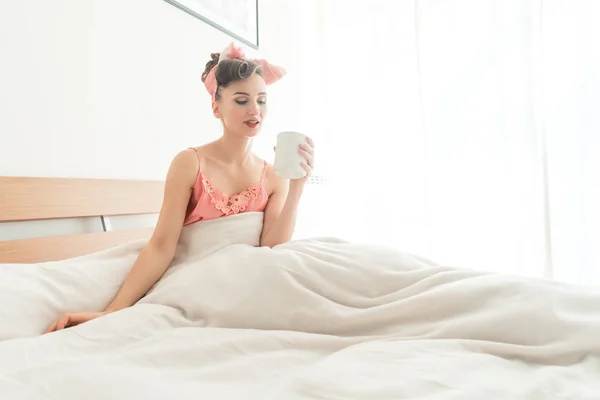 Krásná žena, upíjel svou ranní kávu stále v posteli — Stock fotografie