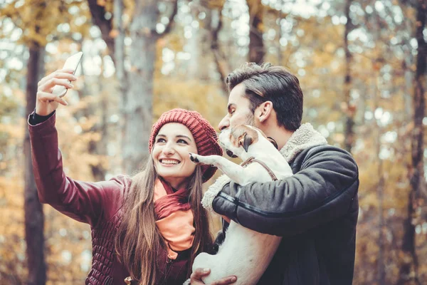 Frau und Mann mit Hund beim Herbstspaziergang und machen ein Handy-Selfie — Stockfoto