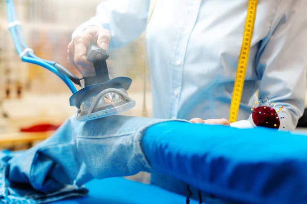 Employee in textile cleaning ironing some trousers — Stock Photo, Image