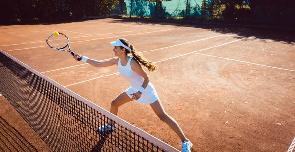Woman hitting the tennis ball on the court