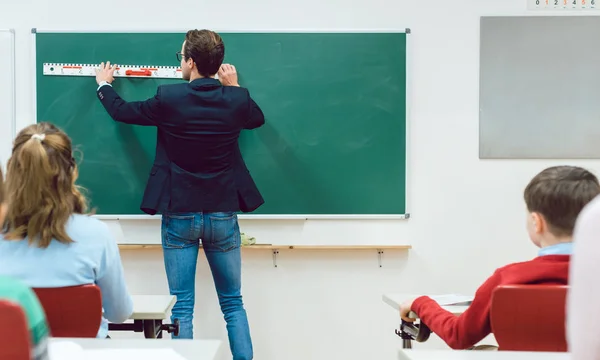 Schüler beobachten Lehrer beim Zeichnen an der Tafel im Klassenzimmer — Stockfoto