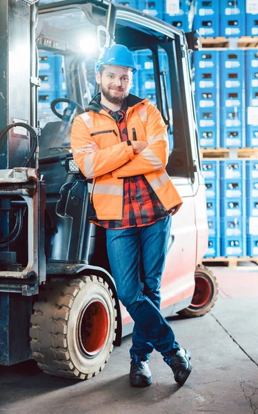 Pracovník v distribučním centru logistiky se svým vysokozdvižním vozíku — Stock fotografie