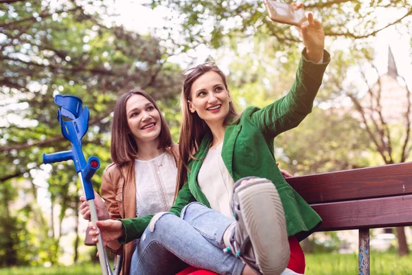 Mujer y su amiga con un esguince de tobillo tomando una foto —  Fotos de Stock