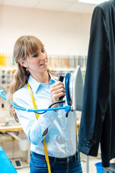 Frau in Textilreiniger bügelt Kleidung — Stockfoto