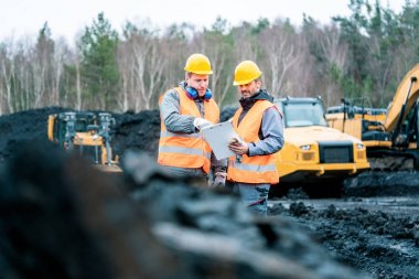 Workers in quarry looking at a plan clipart