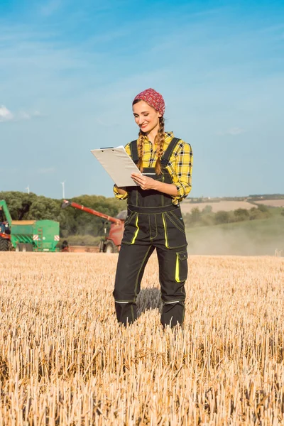 Farmer on the wheat field doing bookkeeping on the ongoing harvest — Stock Photo, Image