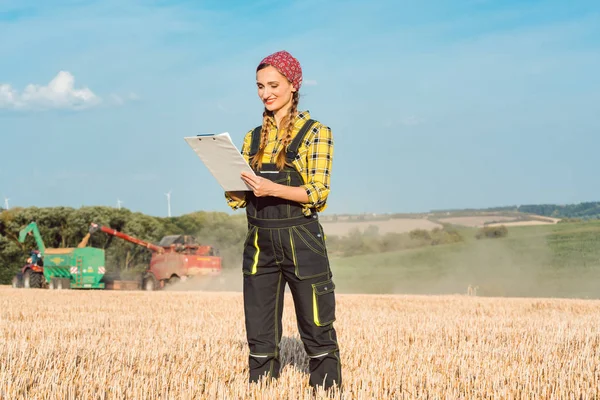 Farmer on the wheat field doing bookkeeping on the ongoing harvest — Stock Photo, Image