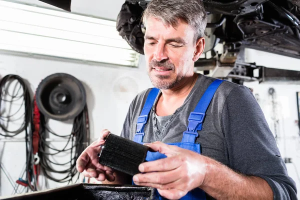 An auto mechanic holding an old, dirty oil filter — Stock Photo, Image