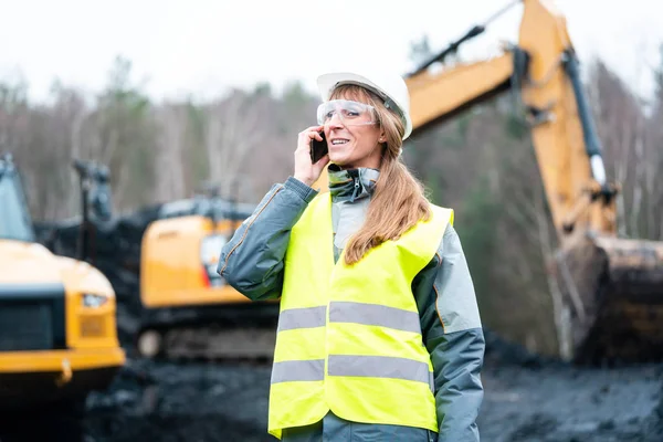 Trabalhador mulher em mineração a céu aberto usando telefone — Fotografia de Stock